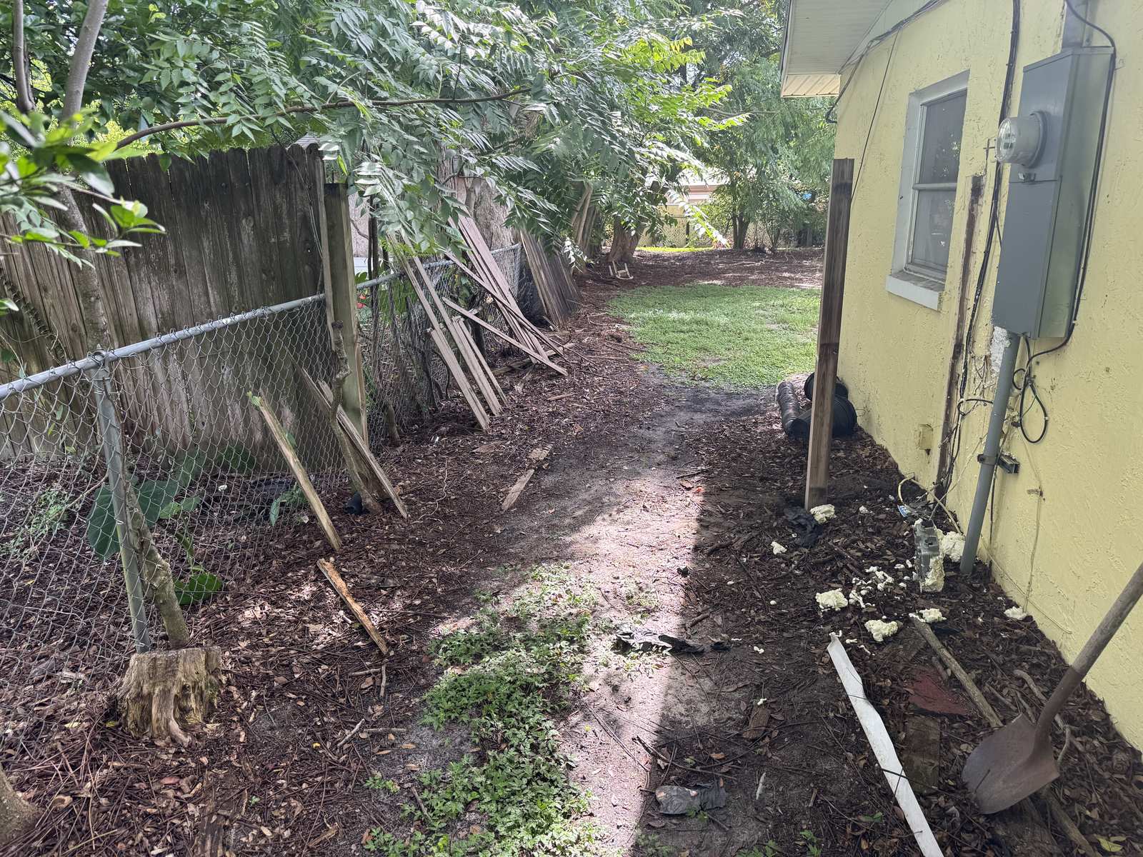 Old wood fence panels down and stacked along the property line