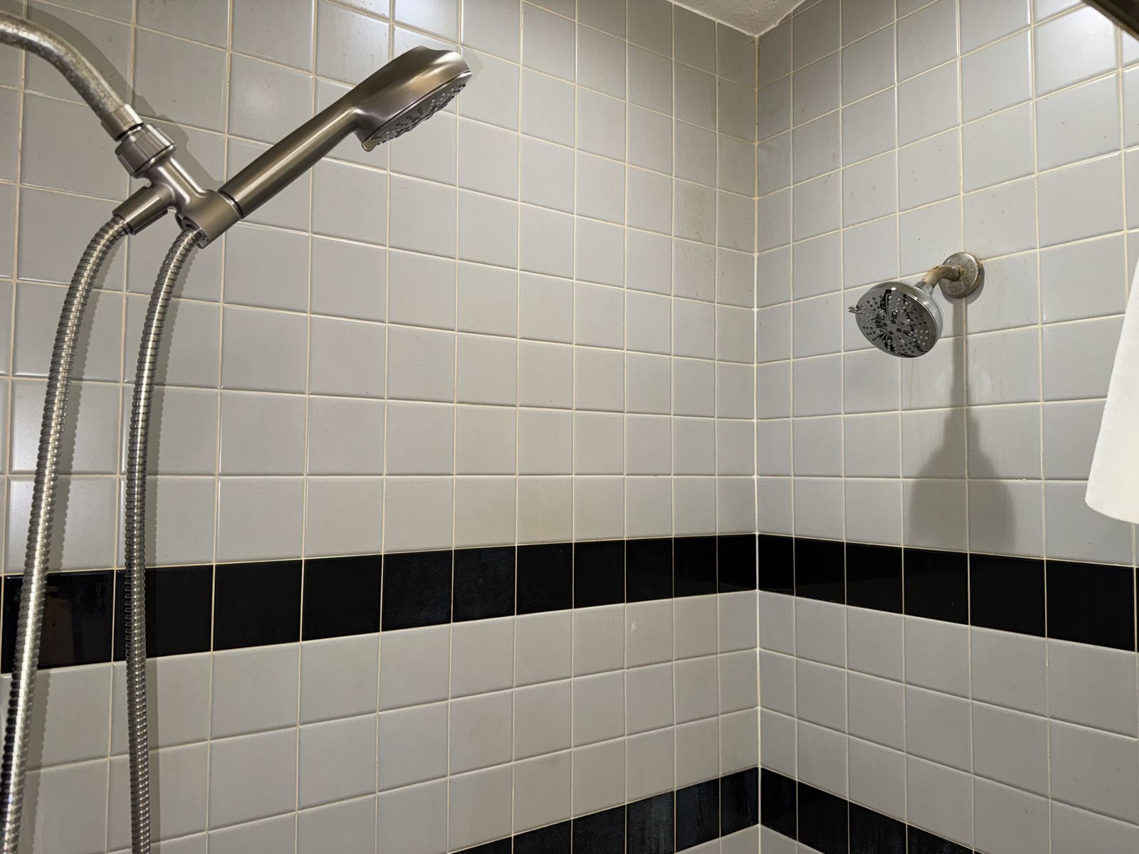 New shower head and handheld sprayer on a tiled wall